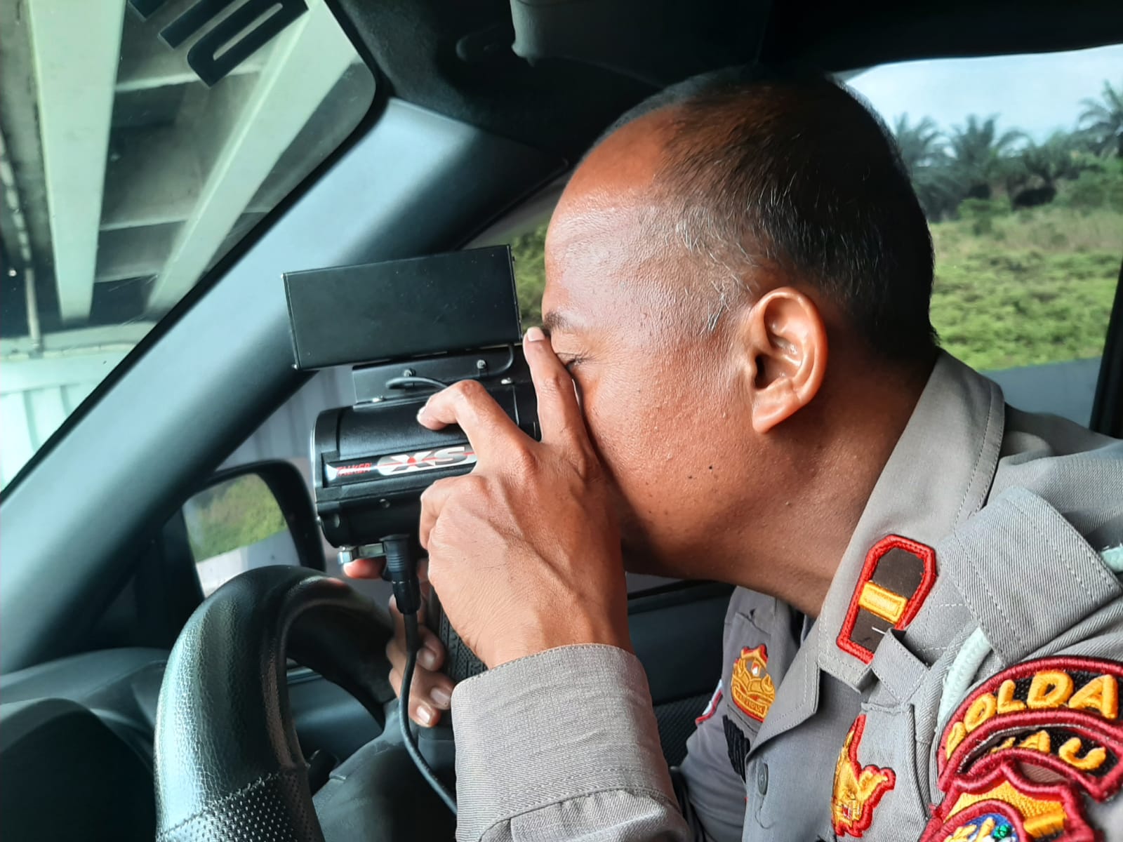 Salah seorang perwira pertama Ditlantas Polda Riau menggunakan Speed Gun untuk mengukur kecepatan laju kendaraan di Tol Permai.