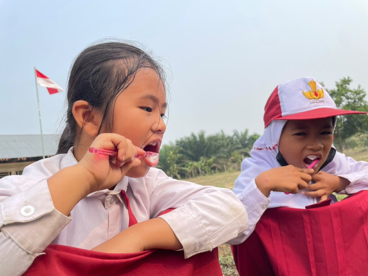 Dua murid SDN 008 Jarak Jauh Pematang Panjang tampak antusias mengikuti gerakan sikat gigi di halaman sekolahnya.