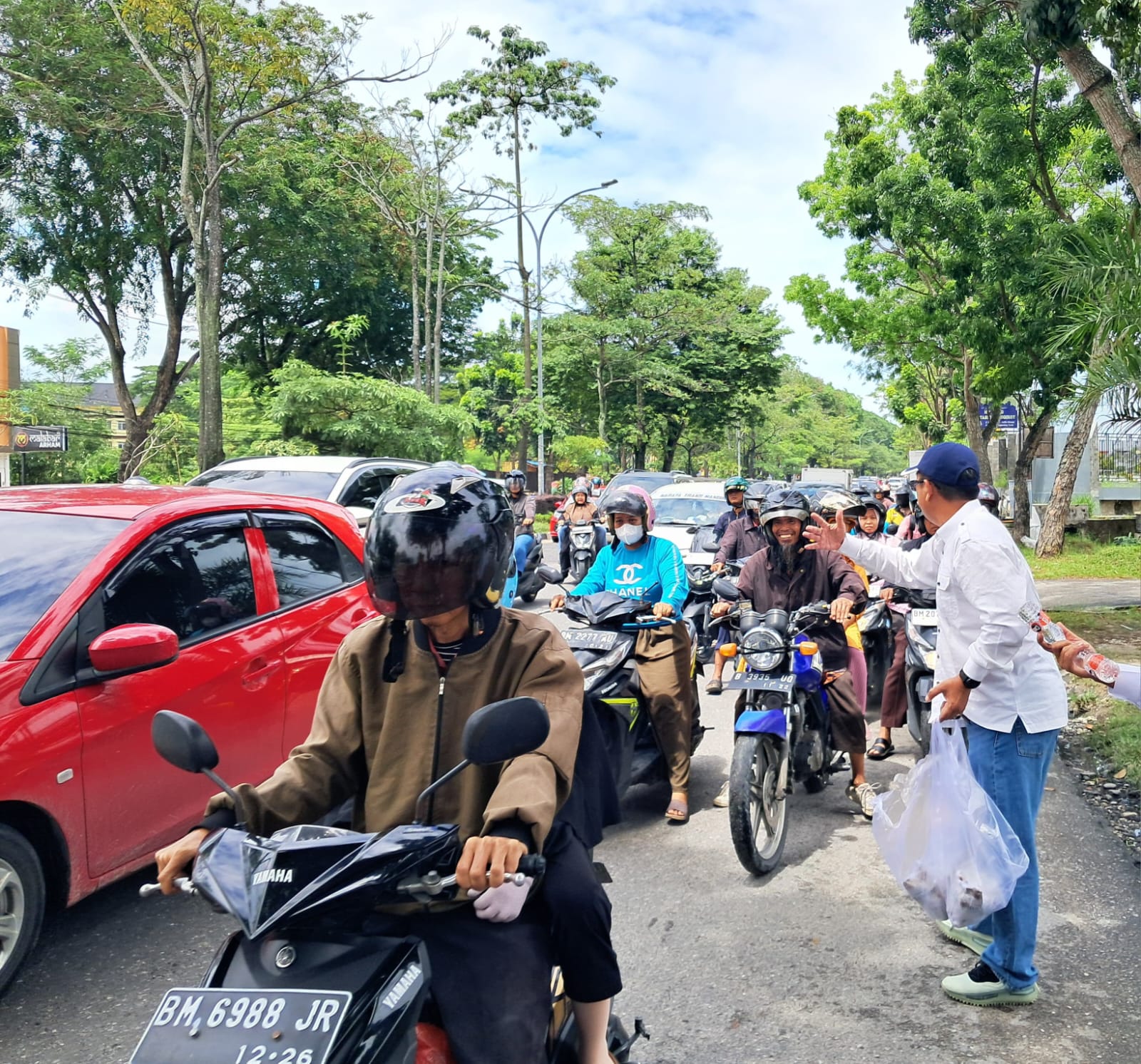 Ketua PWI Riau, Raja Isyam Azwar menyerahkan nasi bungkus kepada pengendara dalam Program Berbagi Jumat Berkah.