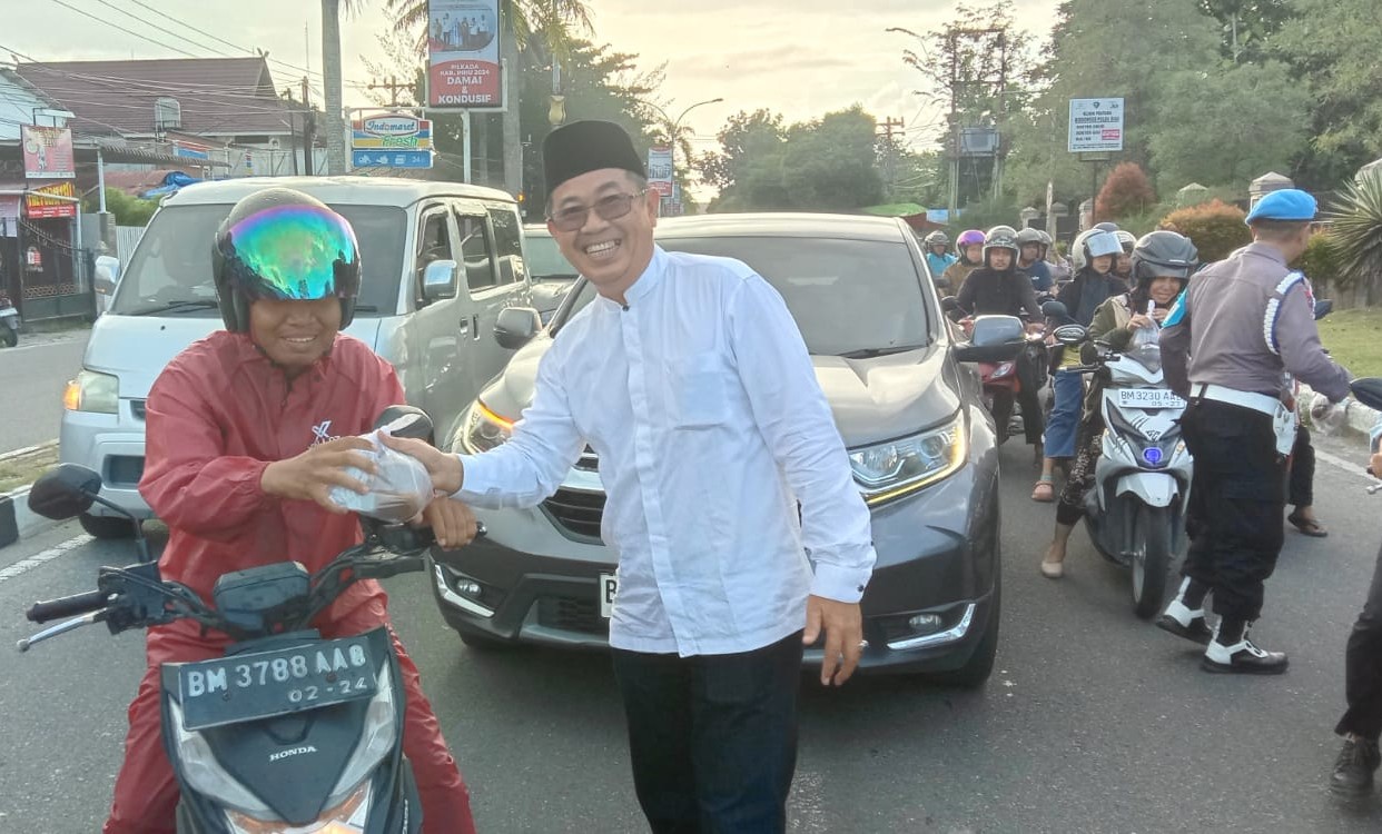 Ketua PWI Riau, H Raja Isyam Azwar membagikan takjil kepada salah seorang pengendara sepeda motor di depan Mapolda Riau.